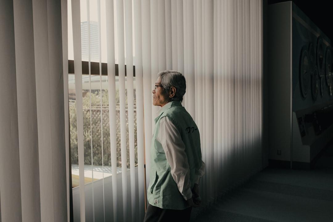 man in gray jacket standing near window