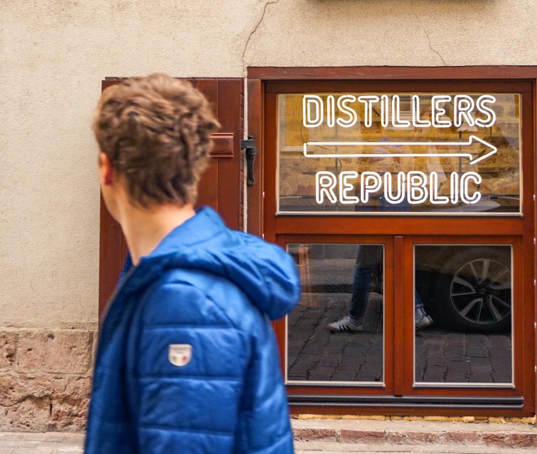 Man walking in front of a LED sign leading to a distillery in Riga, Latvia